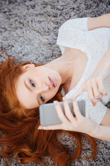 Sticker - Woman lying on the carpet with smartphone