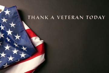 Text Thank A Veteran Today on black background near American flag