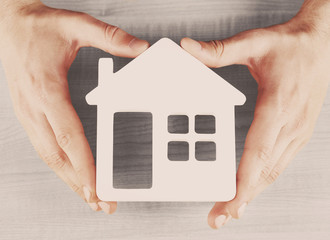 Poster - Male hands holding model of house on wooden background, close-up