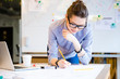 © Drobot Dean - Pretty young woman drawing blueprint by pencil in the office