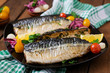 Baked mackerel with herbs and garnished with lemon and pickled vegetables