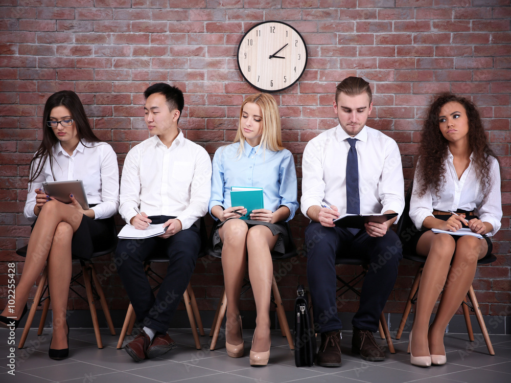 Young people sitting on a chairs in brick wall hall