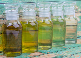  Avocado fruit oil, sesame seed oil, olive oil, grape seed oil and corn oil in vial glass bottle over rustic wooden background