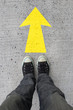 Pair of shoes standing on a road with yellow arrow on concrete background