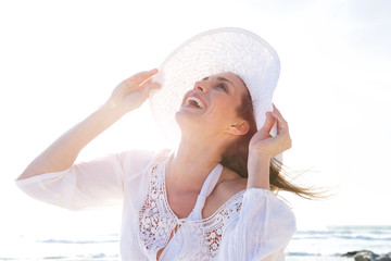 Wall Mural - Older woman laughing with hat at the beach