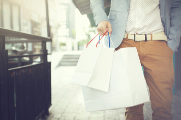 Shopaholic man walking on commercial street with a lot of shopping bags