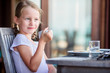 Adorable little girl having breakfast with tea at outdoor cafe