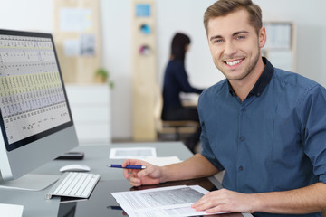 lächelnder mitarbeiter im büro arbeitet am pc