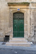 Od gate with ornaments and closed green doors in an old building in a street in Arles, France on a sunny day in the summer
