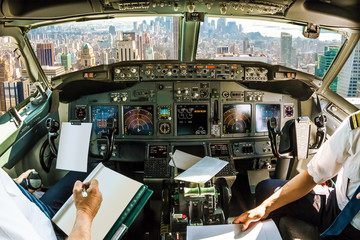 Wall Mural - Flight in airplane cabin interior on New York skyline of United States of America.. Pilots arms and blank white papers for copy space