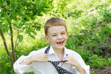 The little boy unties a tie against green