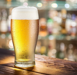 Glass of light beer on the glass bar counter.