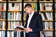 © mintybear - Handsome young man holding books and smiling while standing in library