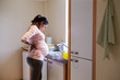 Pregnant Woman With Back Ache Washing Dishes In Kitchen Sink