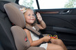 Little girl waves her hand sitting in car seat