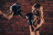© satyrenko - Cute brunette woman training with boxing gloves at the gym against brick wall