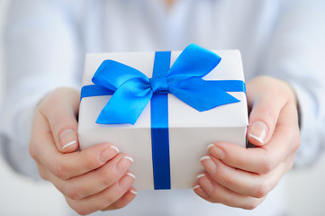 Hands closeup. Gift with blue ribbon in hands.