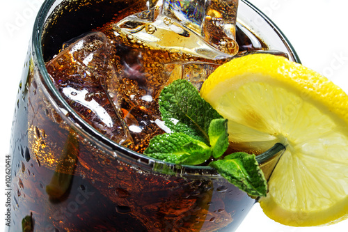 Fotomural top of a glass of cola or coke with ice cubes, lemon slice and peppermint garnish, closeup with selected focus and narrow depth of field