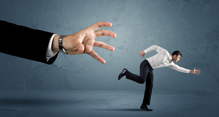 business man running away from a huge hand concept