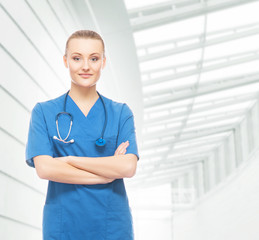 Wall Mural - Beautiful and cheerful intern with stethoscope and blue coat in