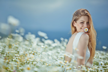 Wall Mural - Beautiful young woman in a camomile field 