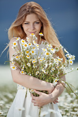 Wall Mural - Beautiful young woman in a camomile field 