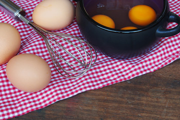 Wall Mural - Eggs and whisk on wooden background