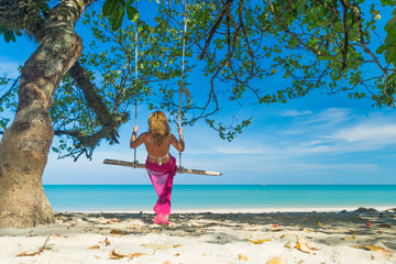 Canvas Print - Woman in blue dress swinging at the beach