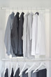 row of white, gray, black shirts with pants hanging in wooden wardrobe