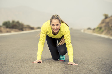 attractive blond sport woman ready to start running practice training race starting on asphalt road mountain landscape