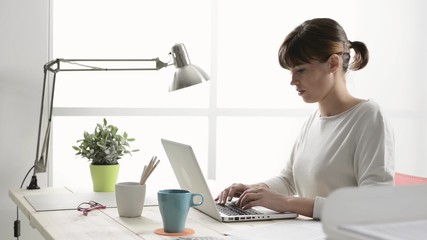 Poster - Businesswoman working at office desk, she is typing on a laptop and networking