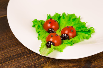 Ladybug made of raw tomato on lettuce leaf