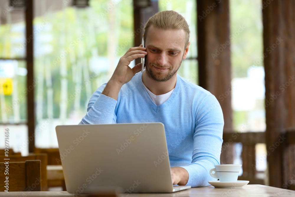 Young attractive businessman having lunch and working in a cafe