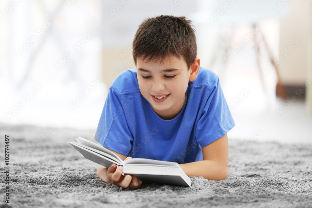 Little boy reading book on a floor at home