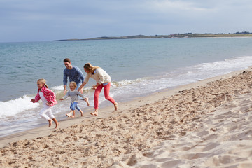 Family On Beach Vacation Running By Sea