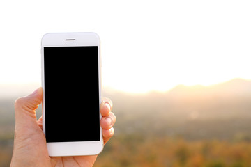 Sticker - Hand holding mockup smartphone with sunlight and mountain backgr