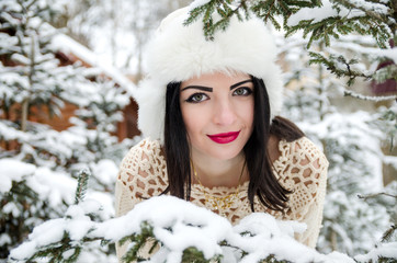 portrait of girl posing under snow-covered trees branches