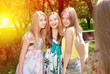 © stormy - Three happy female friends hugging in green summer park sun light outdoors background