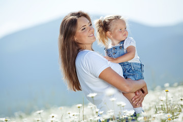 Wall Mural - Mother with daughter on nature in a camomile field 