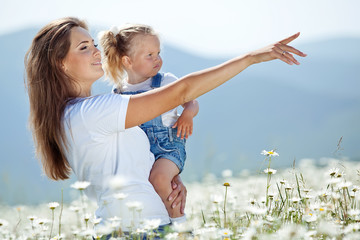 Wall Mural - Mother with daughter on nature in a camomile field 