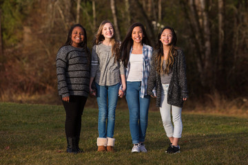 Wall Mural - Group of four pretty young girls with cultural diversity holding