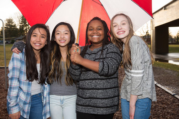 Wall Mural - Group of kids under an umbrella in the rain