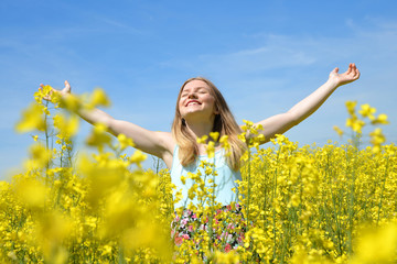 Wall Mural - Young happy woman on blooming rapeseed field in spring