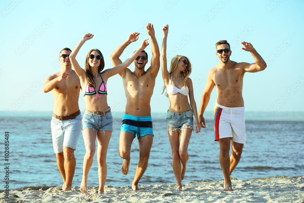 Happy friends running at the beach, outdoors