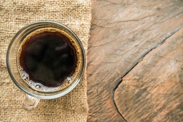 Black Coffee in clear cup put on a sackcloth and wooden table background - copy space & your design