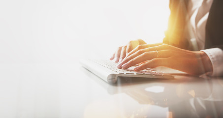 Closeup photo of female hands typing text on a wireless keyboard. Visual effects, white background