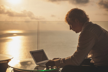 Blond businessman is working on laptop on the tropical islands b