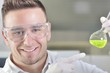 © cirkoglu - Attractive young PhD student scientist observing the green indicator color shift after the solution destillation in chemical laboratory