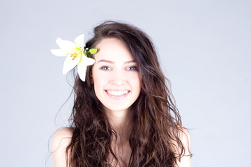 Happy woman with flower in curly hair with smile with teeth. SPA treatment.