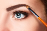 Beautiful female eyes with bright blue make-up and brush